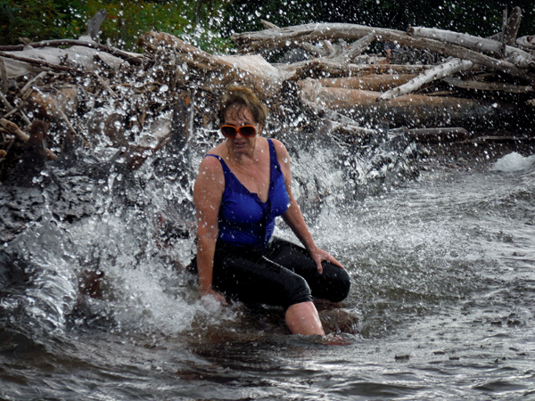 The waves are splashing against the logs and Karen.